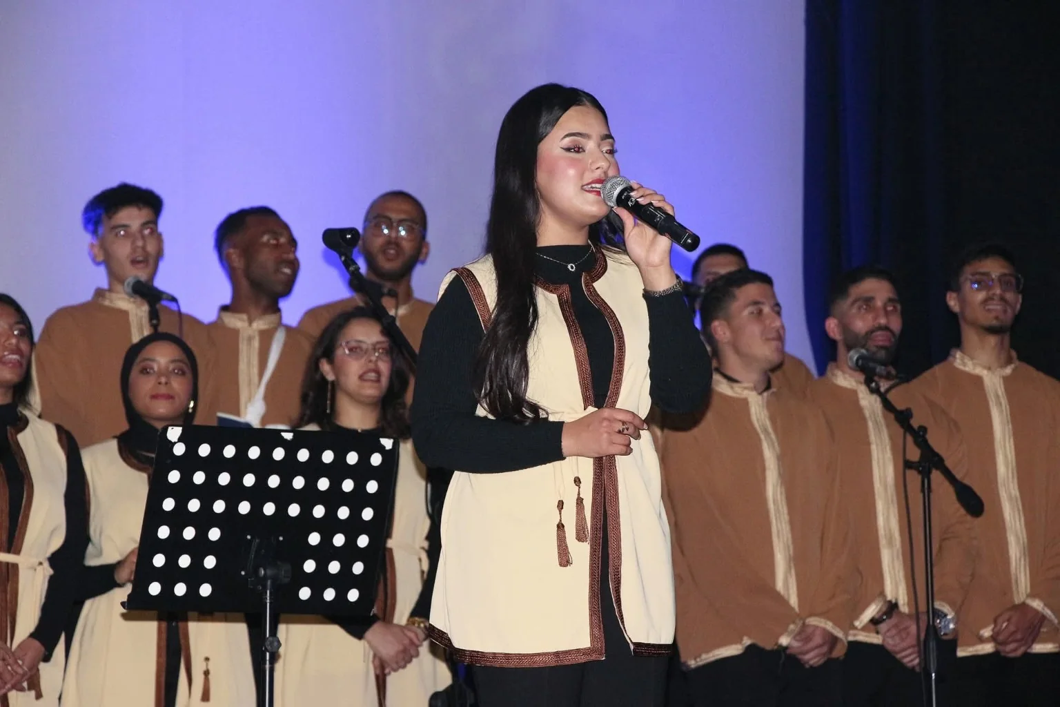 مغنية على الخشبة وخلفها أعضاء الكورال